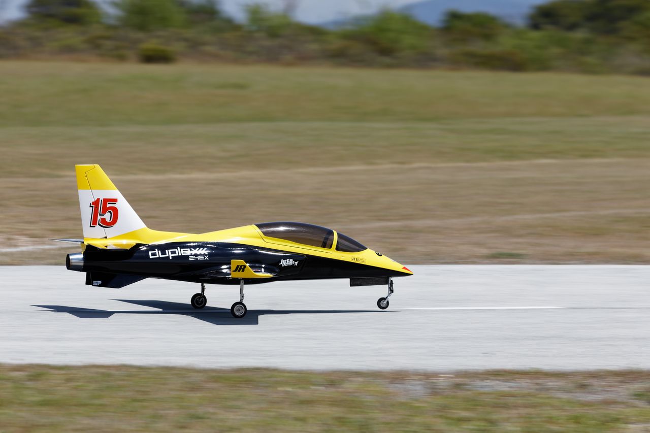Vibrant yellow and black RC jet model speeding on a runway, showcasing dynamic movement and precision.