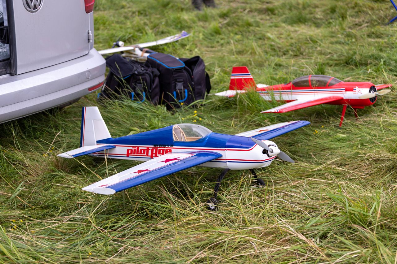 Colorful model airplanes on a grassy field during an outdoor sports event.